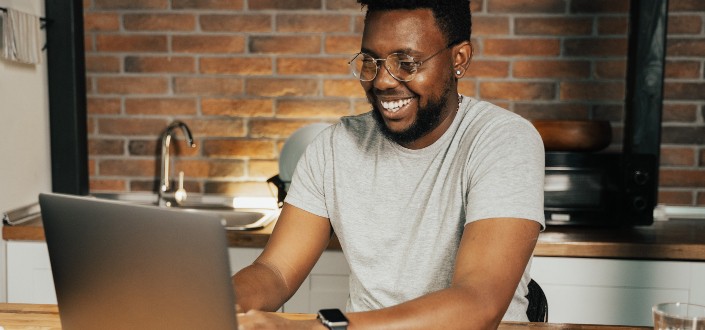 Man with glasses smiling while typing