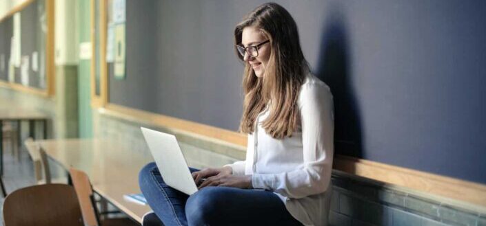 Woman Sitting on Table While Using Macbook