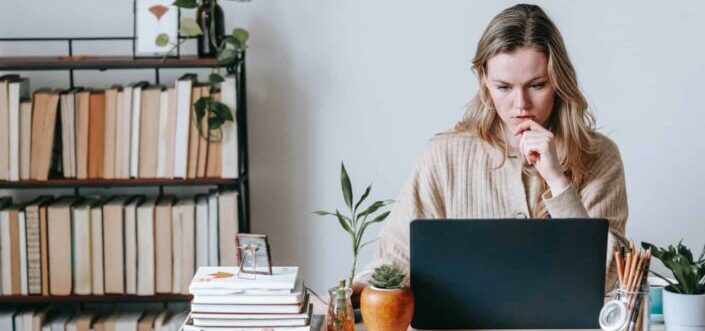 woman browsing laptop near books